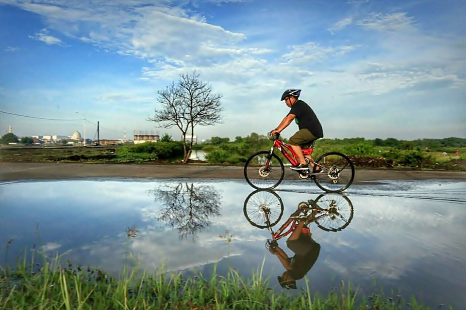 Bersepeda Sambil Manfaatkan Genangan Air Jadi Objek Foto Refleksi